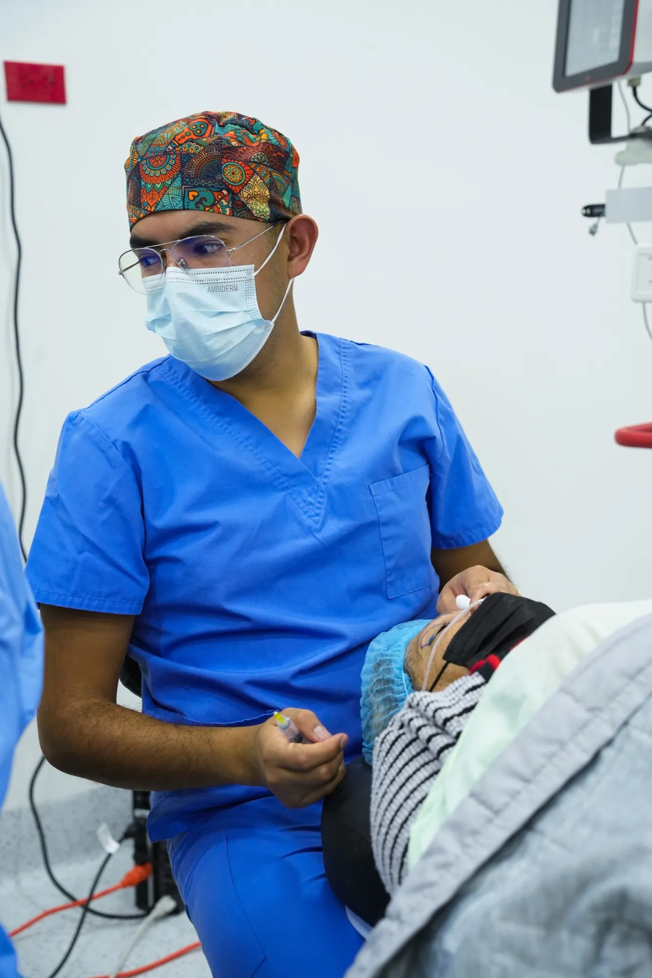 El Dr. Cervantes, con uniforme quirúrgico, prepara a una paciente en el quirófano de EyeCare