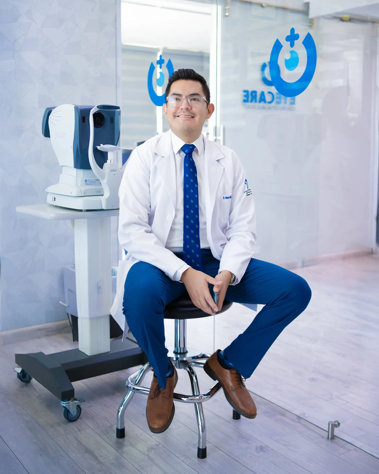 El Dr. Roberto Cervantes Drago con bata blanca junto al autorrefractómetro en EyeCare