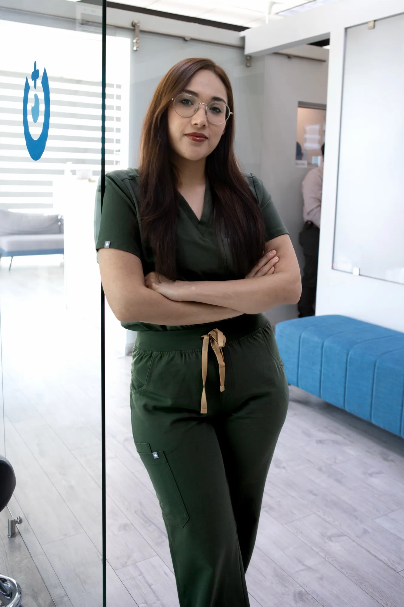 Asistente de EyeCare con uniforme verde, de brazos cruzados, en la recepción