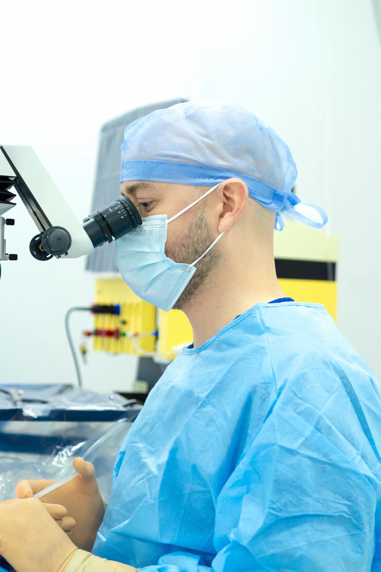 El Dr. César Hernández, con gorro y cubrebocas, en el microscopio del quirófano de EyeCare